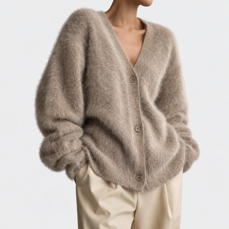 Woman wearing an oversized, fuzzy, light brown cardigan with a V-neck and three visible buttons over beige pants.