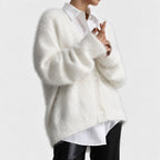 Woman wearing a soft, fluffy white cardigan with ribbed cuffs and visible buttons over a white shirt and black pants.