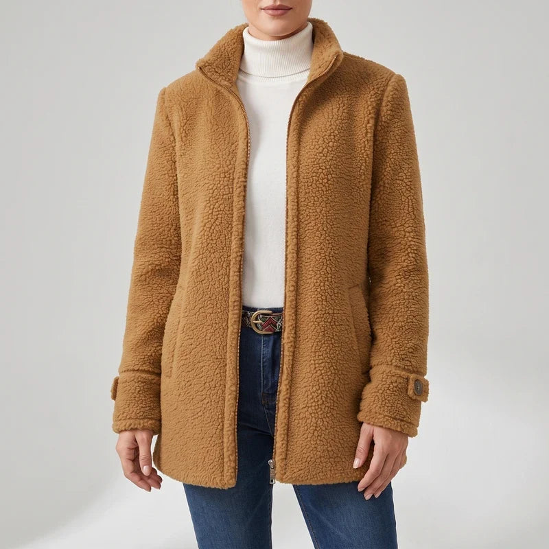 Woman wearing a warm, textured brown teddy coat with a high collar, zipper front, and buttoned cuff tabs over a white turtleneck.