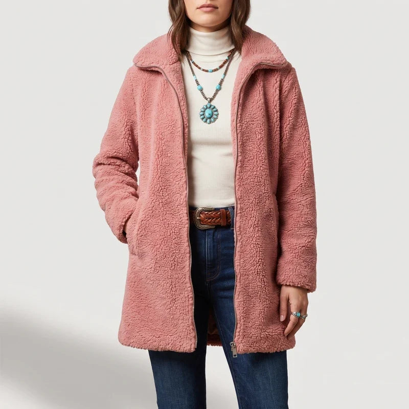 Woman wearing a pink fuzzy coat with a zipper closure, over a cream turtleneck, jeans, and a braided belt.