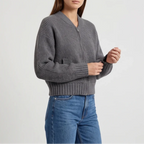 Woman wearing a dark grey ribbed knit cropped zip-up cardigan with a collarless V-neck, paired with blue jeans.