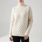 Woman wearing a cream-colored turtleneck sweater with a basketweave cable-knit pattern, paired with black pants.