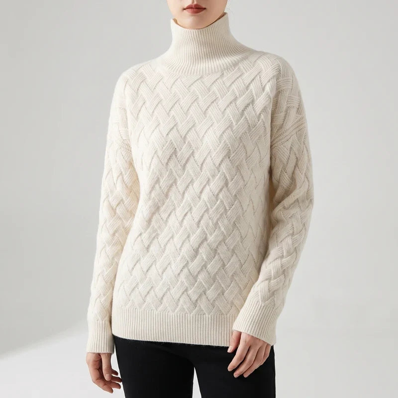 Woman wearing a cream-colored turtleneck sweater with a basketweave cable-knit pattern, paired with black pants.