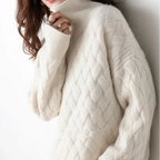 Woman wearing a cream turtleneck sweater with an intricate diamond cable knit pattern, casually holding the collar.