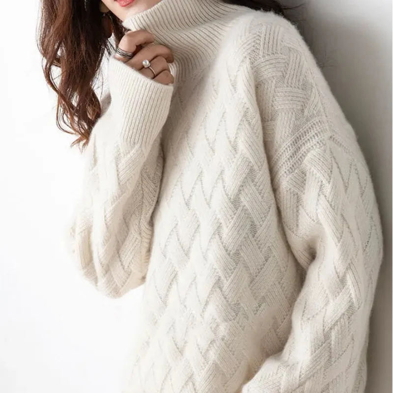 Woman wearing a cream turtleneck sweater with an intricate diamond cable knit pattern, casually holding the collar.