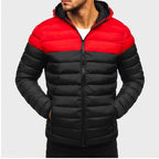 Man wearing a two-toned red and black hooded puffer jacket with hands in side pockets, full zipper visible.