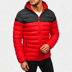 Man wearing a red and black two-tone hooded puffer jacket with a visible zipper over a white t-shirt.