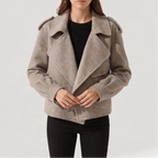 Woman wearing a light brown moto-style jacket with wide lapels, shoulder tabs, and two front pockets over a black top.