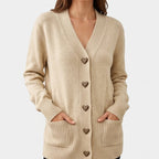 Woman wearing a beige knit cardigan with a V-neck, leopard-print heart buttons, ribbed cuffs, and two front pockets.