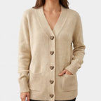 Woman wearing a beige knit cardigan with V-neck, heart-shaped leopard print buttons, ribbed cuffs, and two front pockets.