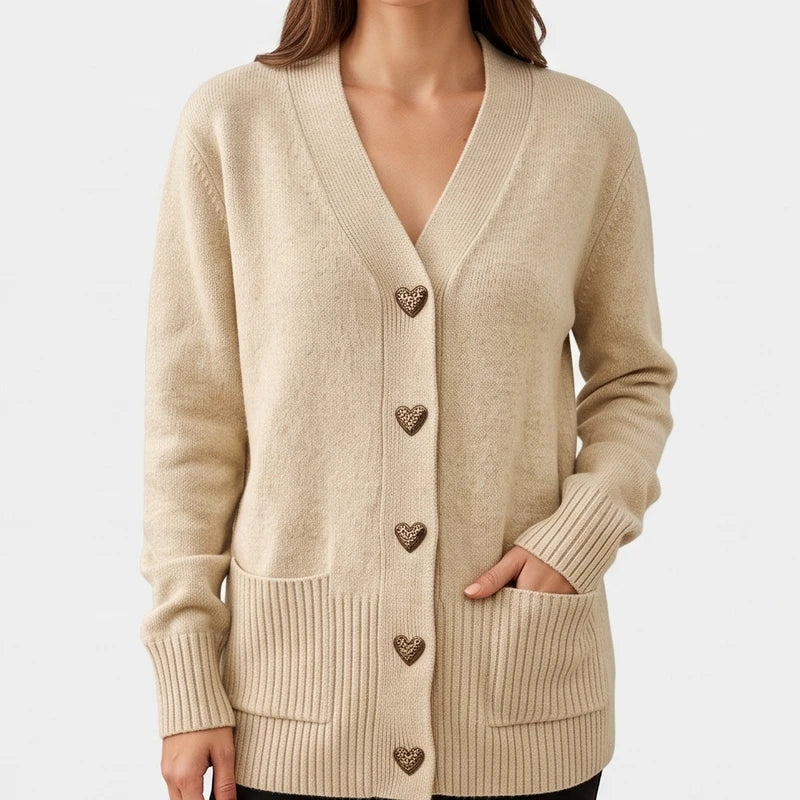 Woman wearing a beige knit cardigan with V-neck, heart-shaped leopard print buttons, ribbed cuffs, and two front pockets.