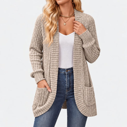 Woman wearing a long, open-front ribbed knit cardigan in a light beige color, with front pockets and long sleeves, over jeans.
