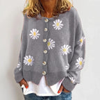Woman wearing a gray knit cardigan with a white daisy pattern, large button closure, and ribbed hem, over a white top.