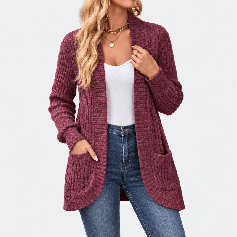 Woman wearing a long, open-front ribbed knit cardigan in deep maroon with two front pockets, over a white top and jeans.