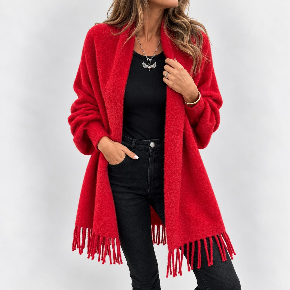 Woman wearing a long, fuzzy red knit cardigan with fringe, over a black top and black jeans.