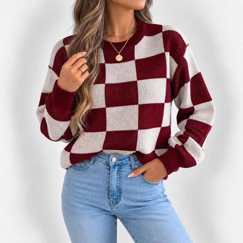 Woman wearing a relaxed-fit, burgundy and cream checkered knit sweater with light wash jeans.