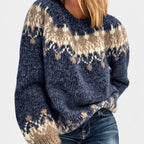 Woman wearing a relaxed-fit, chunky knit navy blue sweater with a cream and beige fair isle pattern.