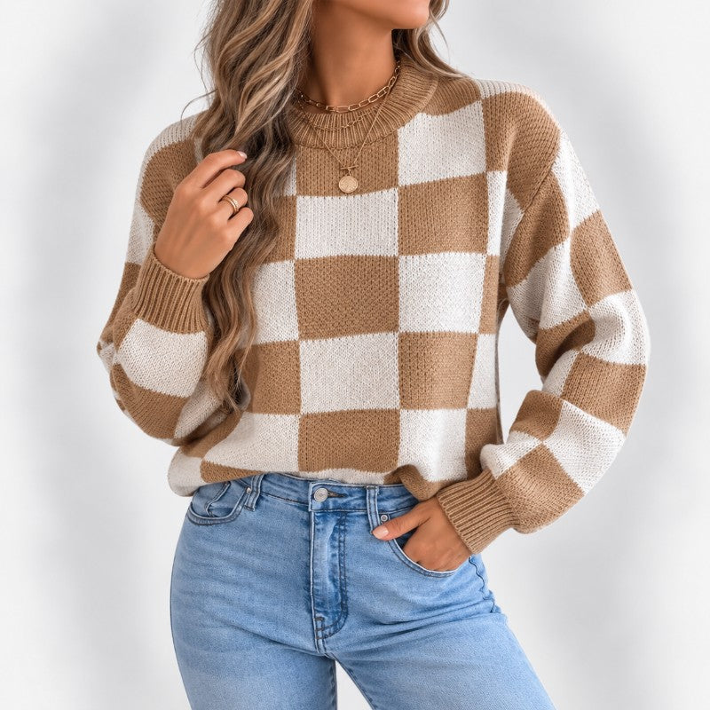 Woman wearing an oversized brown and cream checkered knit sweater with ribbed cuffs and light wash jeans.