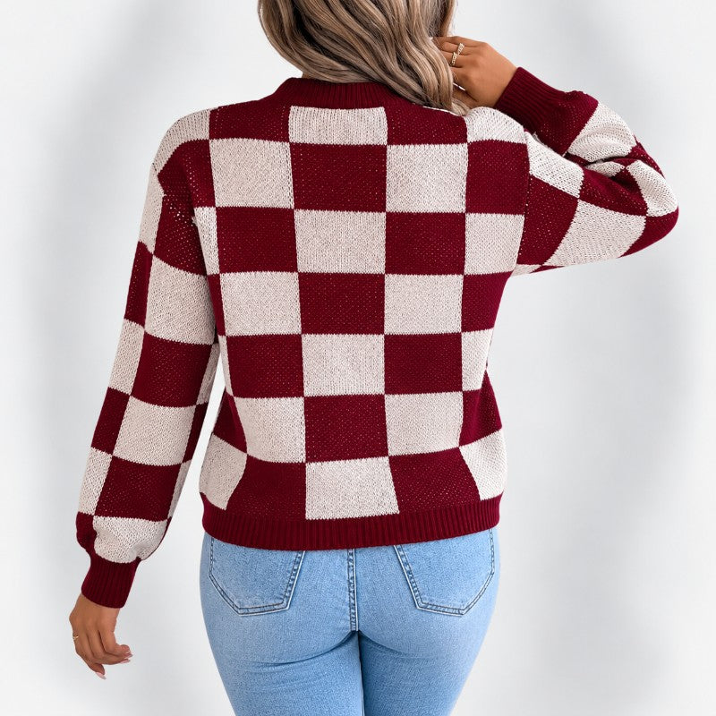 Woman wearing a long-sleeved, maroon and cream checkered knit sweater and light wash jeans, shown from the back.