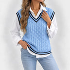 Woman wearing a light blue cable knit sweater vest with black and white striped trim over a white collared shirt and light wash jeans.