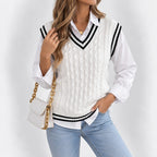 Woman wearing a white cable knit sweater vest with black striped V-neck over a white shirt and light blue jeans.