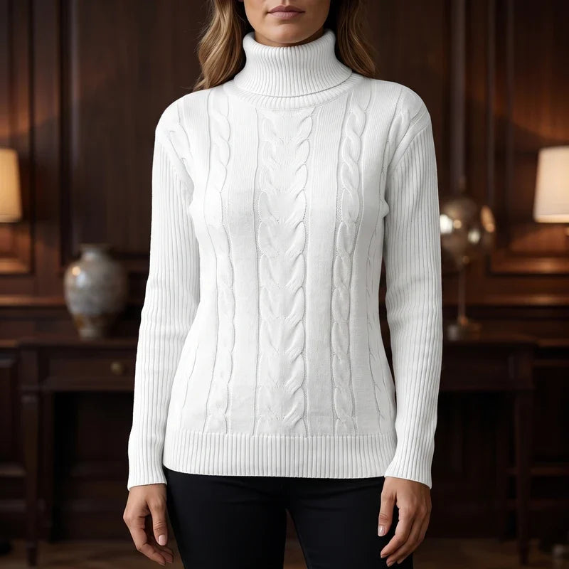 Woman wearing a white cable knit turtleneck sweater with ribbed cuffs and hem, standing in a dim room.