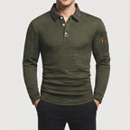 Man wearing a dark olive green long sleeve waffle knit polo shirt with a three-button placket and a zippered sleeve pocket.