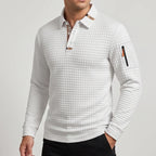 Man wearing a light gray quilted long-sleeve polo shirt with a plaid collar lining and a zippered pocket on the left sleeve.