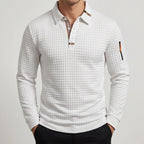 Man wearing a white quilted long-sleeve polo shirt with a plaid collar lining and a small zippered sleeve pocket.