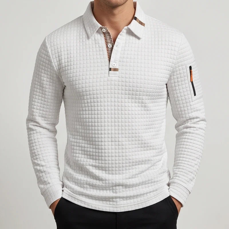 Man wearing a white quilted long-sleeve polo shirt with a plaid collar lining and a small zippered sleeve pocket.