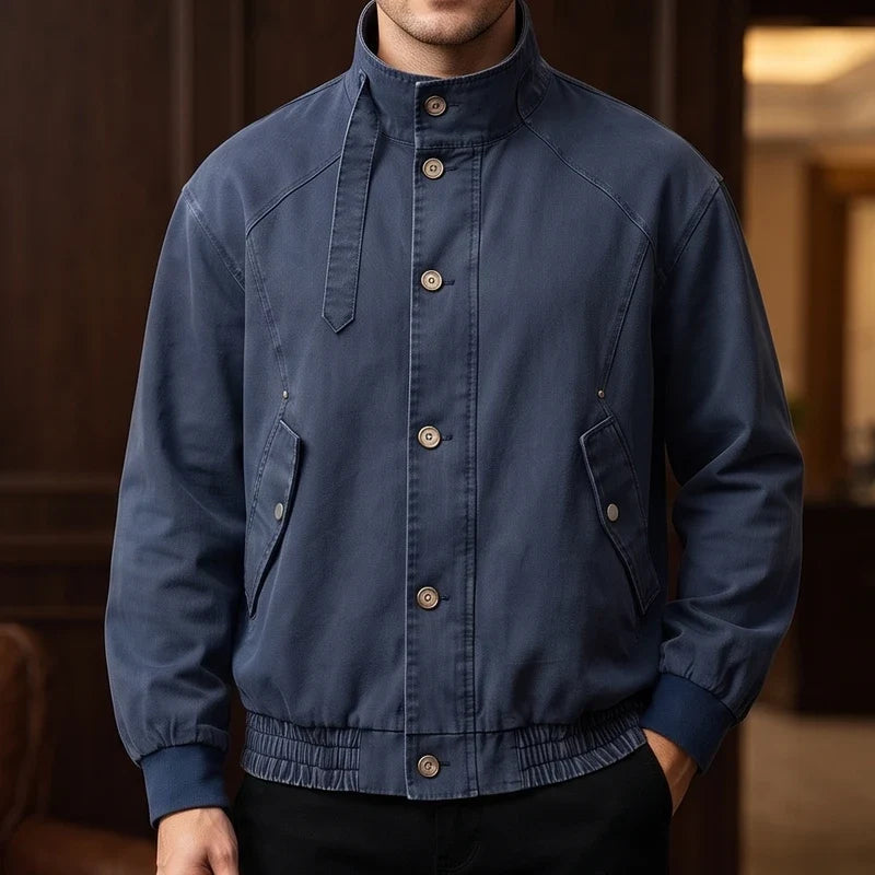 Man wearing a dark blue bomber jacket with a button-front closure, stand-up collar, and ribbed cuffs.