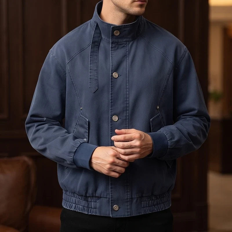 Man wearing a dark blue bomber jacket with a stand collar, snap buttons, and ribbed cuffs and hem.