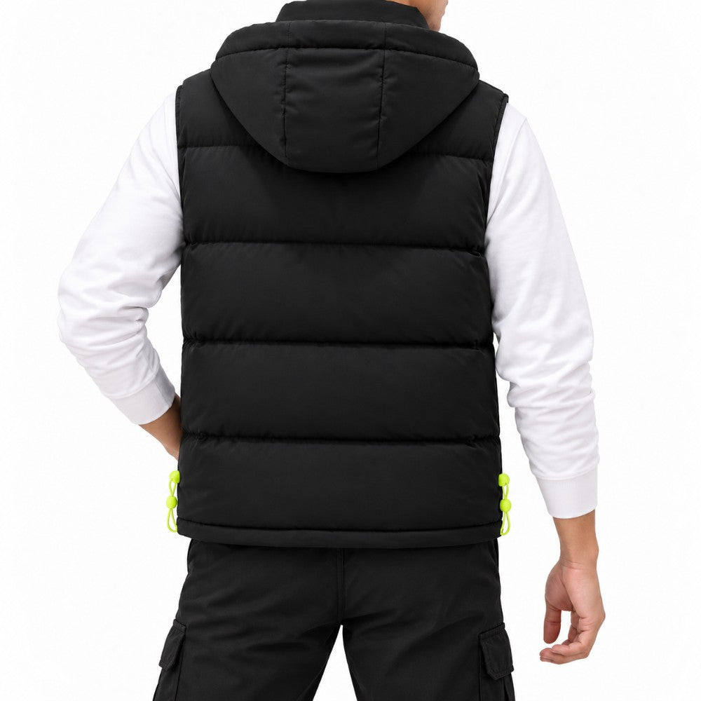 Man wearing a black puffer vest with horizontal baffles and a hood, standing with one hand in his pocket.