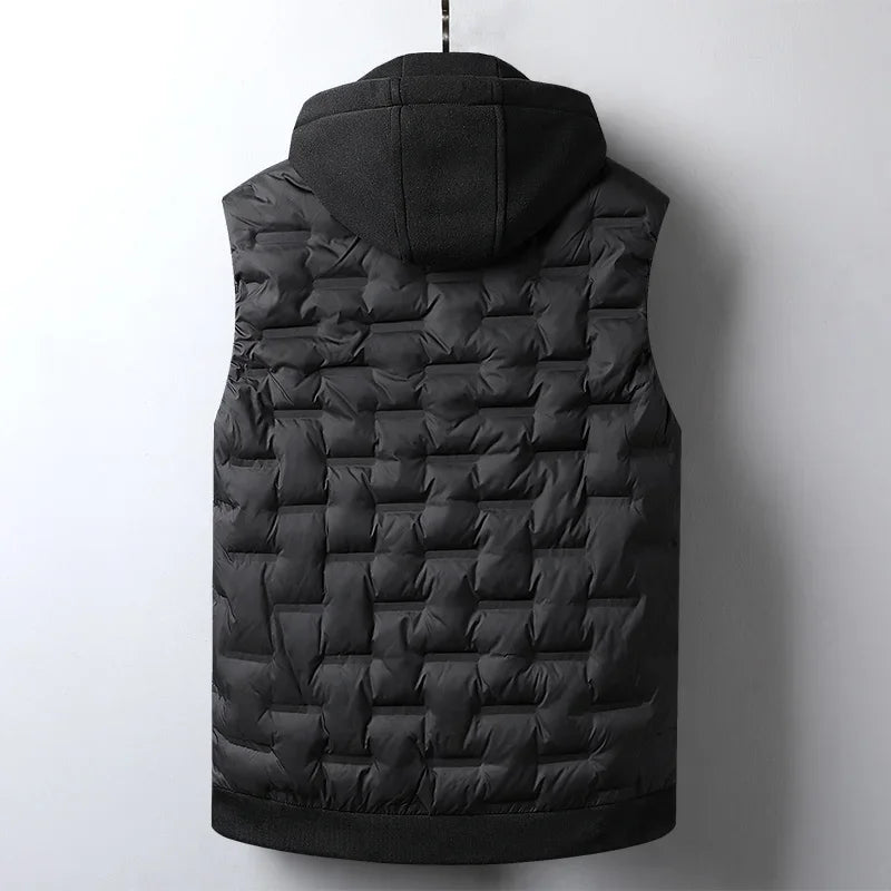 Back view of a black quilted vest with a textured dark gray hood, hanging against a light gray wall.