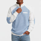 Man wearing a light blue and white color-block waffle knit half-zip sweatshirt with a white chest pocket, posing casually.