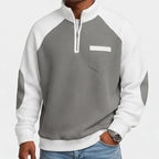 Man wearing a grey and white waffle knit half-zip sweatshirt with a chest pocket and elbow patches.