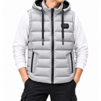 Man wearing a light gray hooded puffer vest with black zippers, black drawstrings, and zippered pockets over a white long-sleeve shirt.