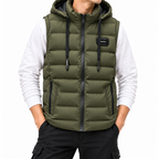 Man wearing a dark olive green puffer vest with a black zipper, hooded collar, and angled zippered pockets over a white long-sleeve shirt.