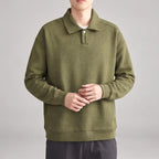 Man wearing an olive green long-sleeve polo shirt with a textured diagonal pattern and a single white button.