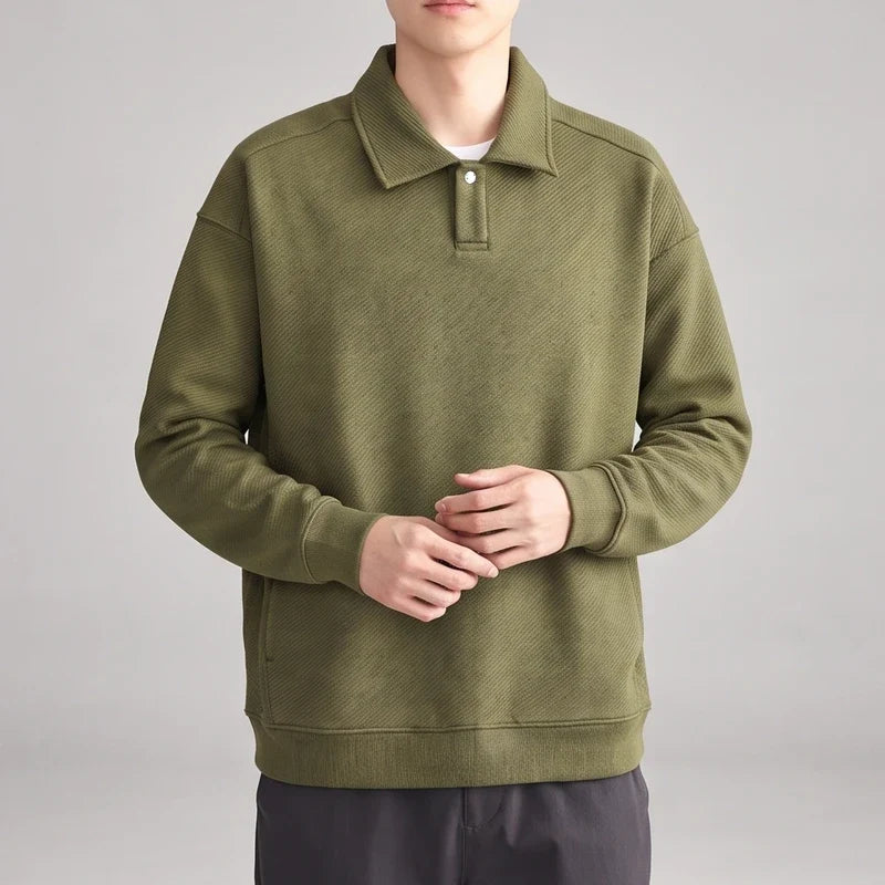 Man wearing an olive green long-sleeve polo shirt with a textured diagonal pattern and a single white button.