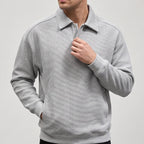 Man wearing a light gray long-sleeve collared sweatshirt with a diagonal ribbed texture and a two-button placket, hand in pocket.