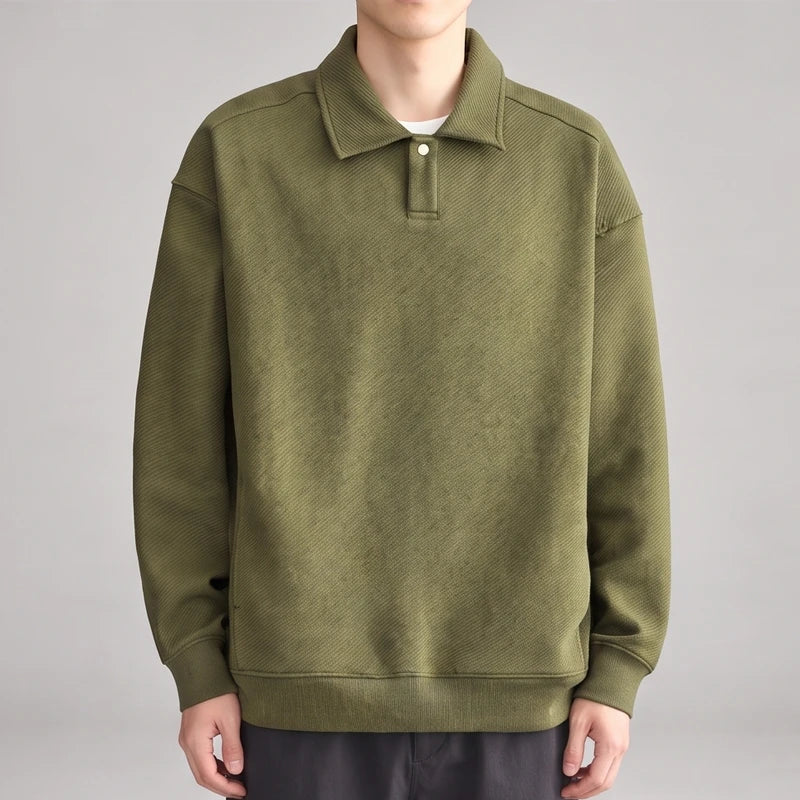 Man wearing an olive green long-sleeve polo shirt with a subtle diagonal textured pattern and a single white button.