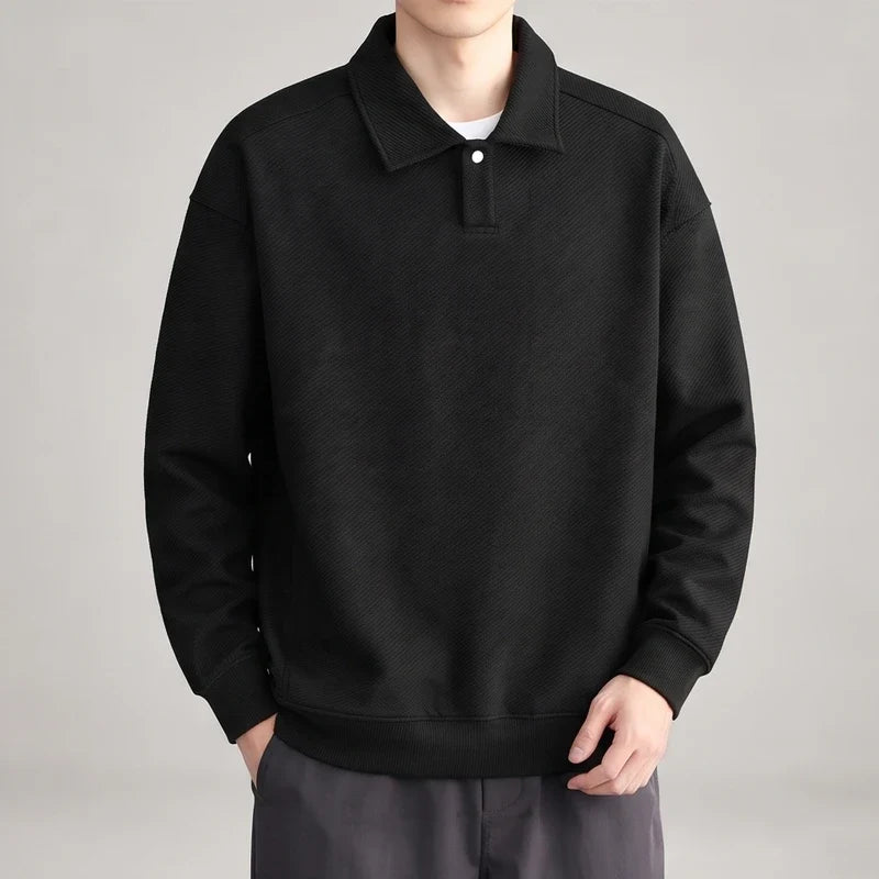 Man wearing a black long-sleeve polo sweatshirt with a textured diagonal stripe pattern and single white button closure.