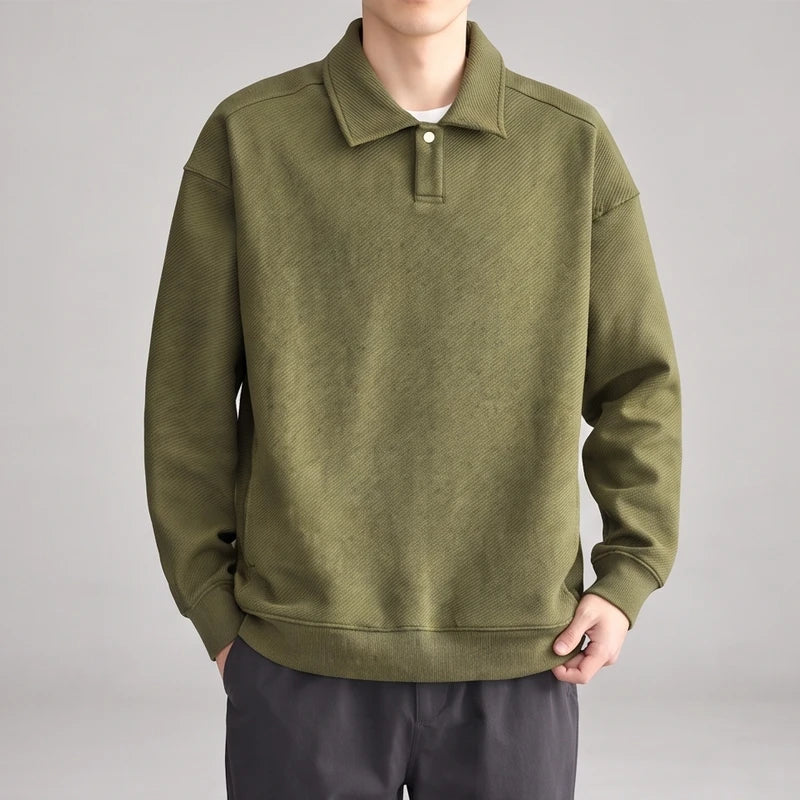 Man wearing a relaxed-fit olive green long-sleeve polo sweatshirt with a diagonal ribbed texture and a single button placket.