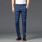 Man wearing blue plaid straight-leg trousers with thin gray checks, a white shirt, brown watch, and black loafers.