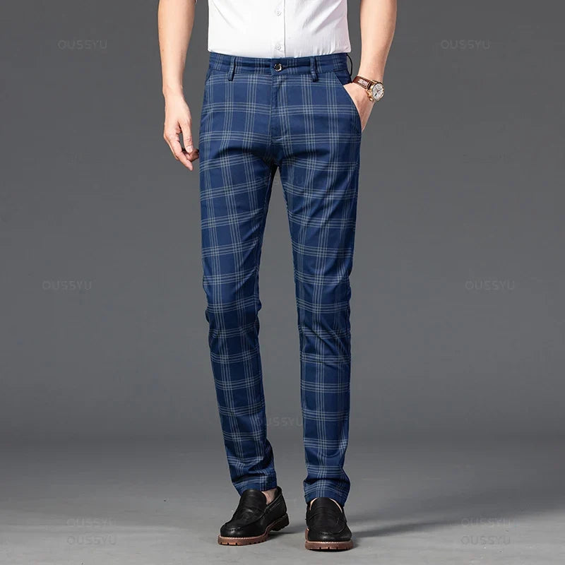 Man wearing blue plaid straight-leg trousers with thin gray checks, a white shirt, brown watch, and black loafers.