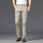 Man wearing light beige straight-leg trousers with a subtle brown plaid pattern, standing with one hand in a pocket.