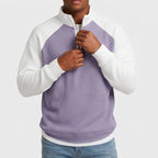 Man wearing a purple and white color-blocked waffle knit quarter-zip, his hands adjusting the zipper.