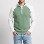 Man wearing a two-tone green and white waffle knit quarter-zip pullover with light blue jeans, hands in pockets.