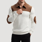Man wearing a white ribbed knit quarter-zip jumper with a brown collar and elbow patches, partially zipped.
